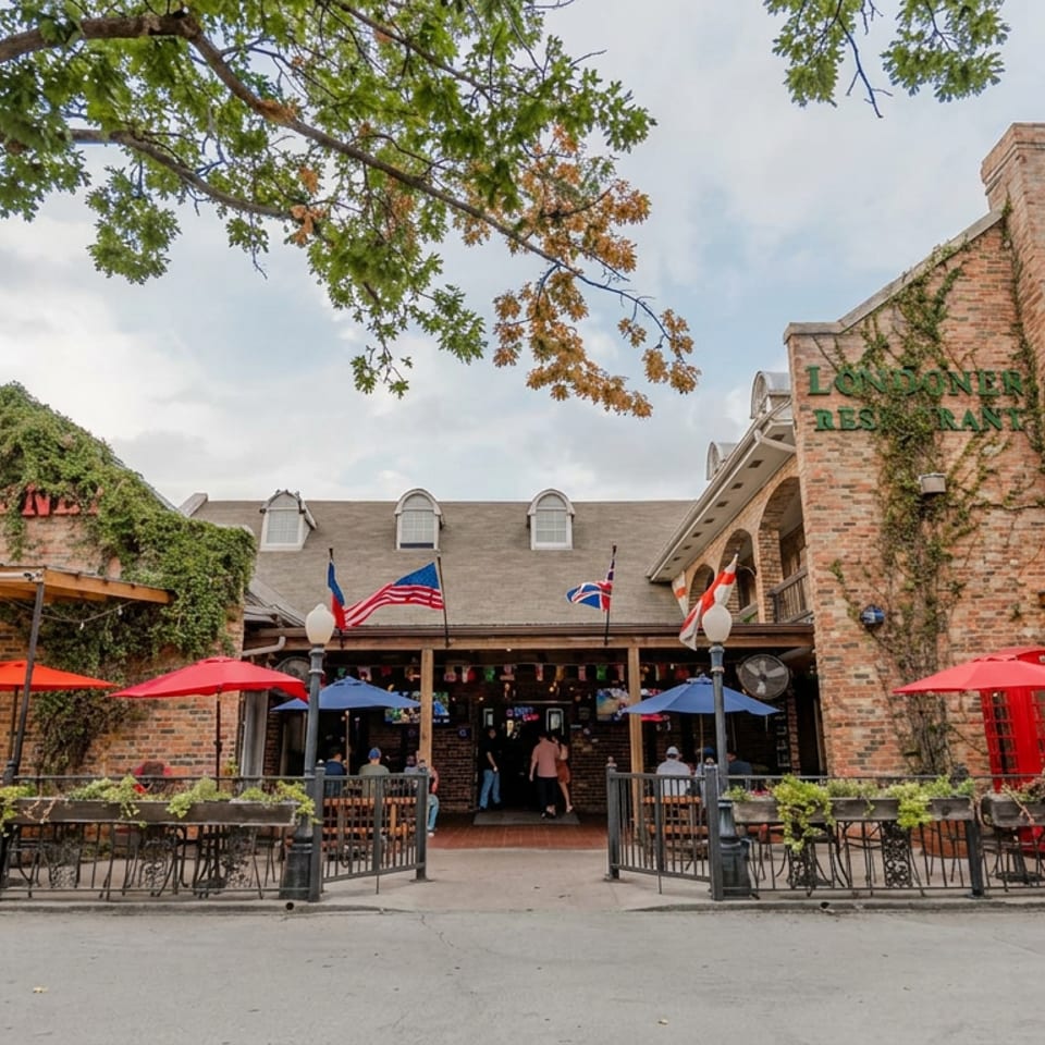 Brick Lone Star restaurant exterior with ivy, outdoor patio seating, colorful umbrellas, flags, and a red British phone booth.