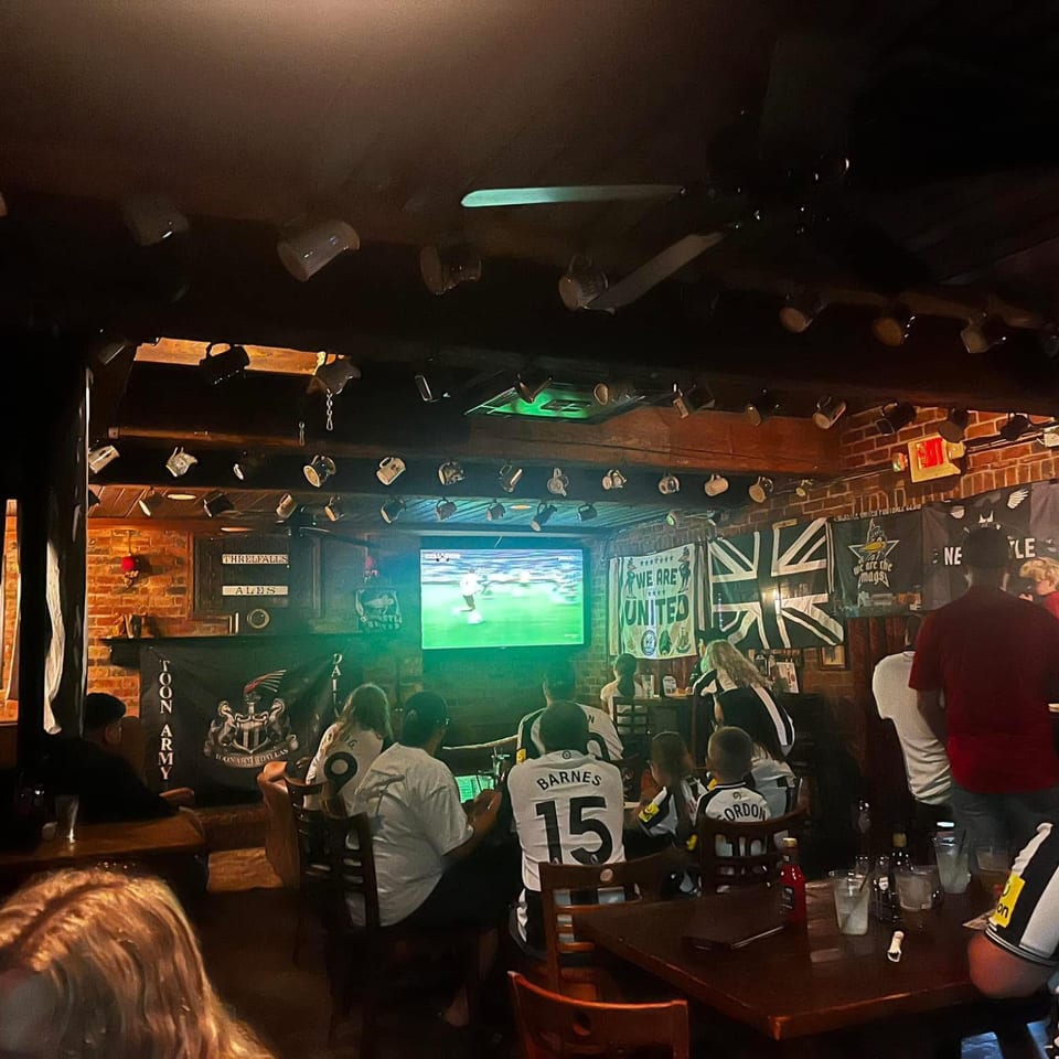 Newcastle supporters watching a match inside the pub with Toon Army banners.