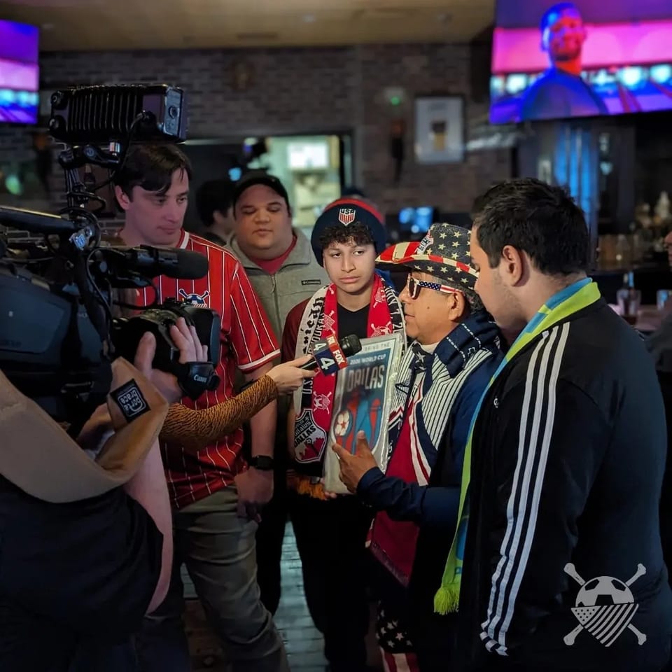 American Outlaws Dallas supporters being interviewed by a camera crew inside the pub.
