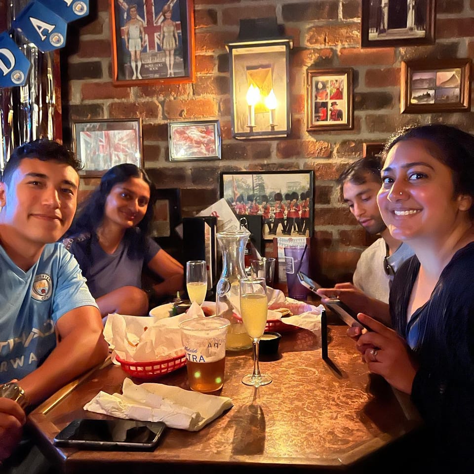 Manchester City supporters sharing food and drinks around a table at the pub.