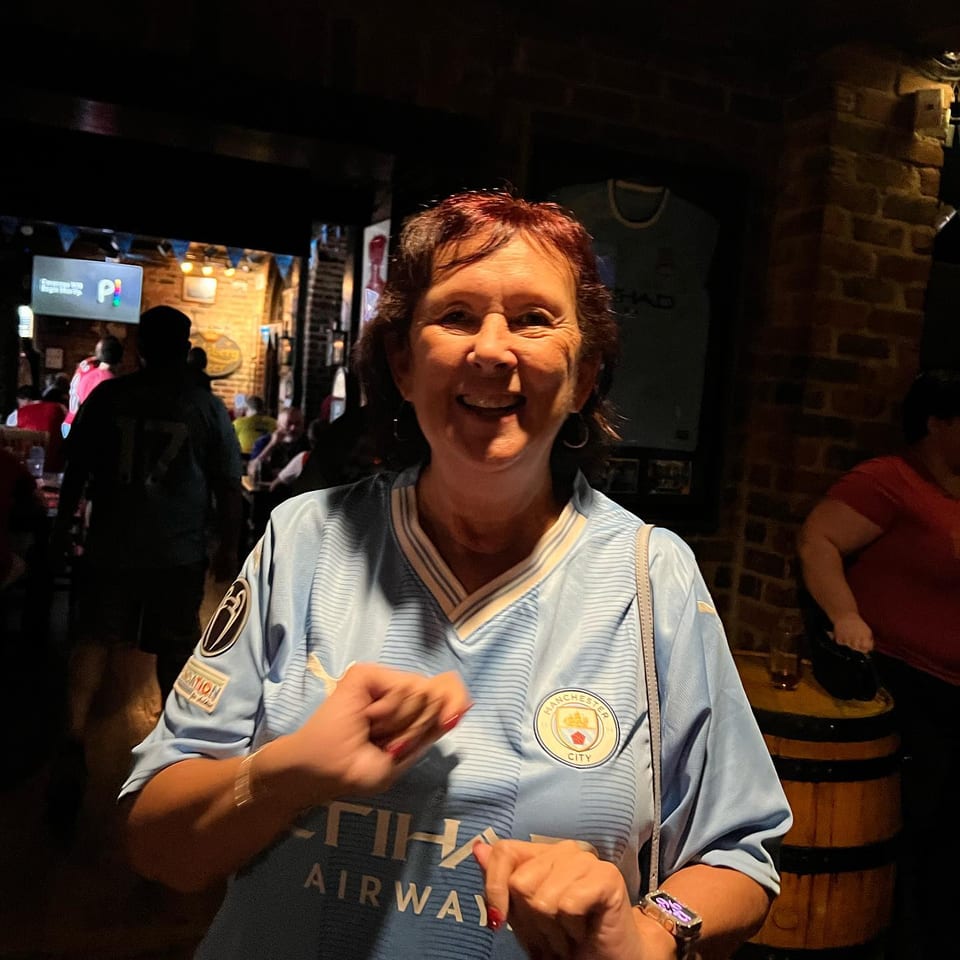 Manchester City supporter wearing a sky-blue shirt inside the pub.