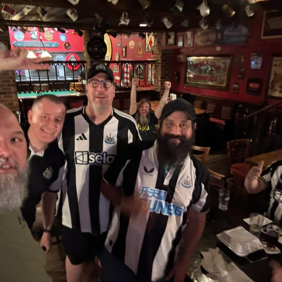 Toon Army Dallas supporters in Newcastle shirts posing together inside the pub.
